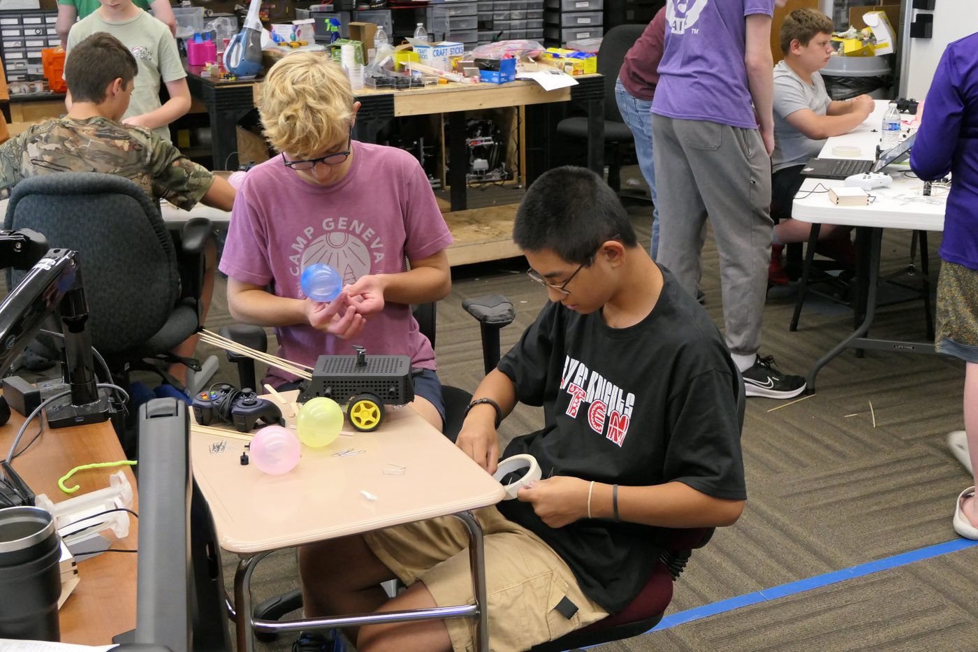 Crusader Robotics campers building a small battle bot at a worktable during the summer STEM camp