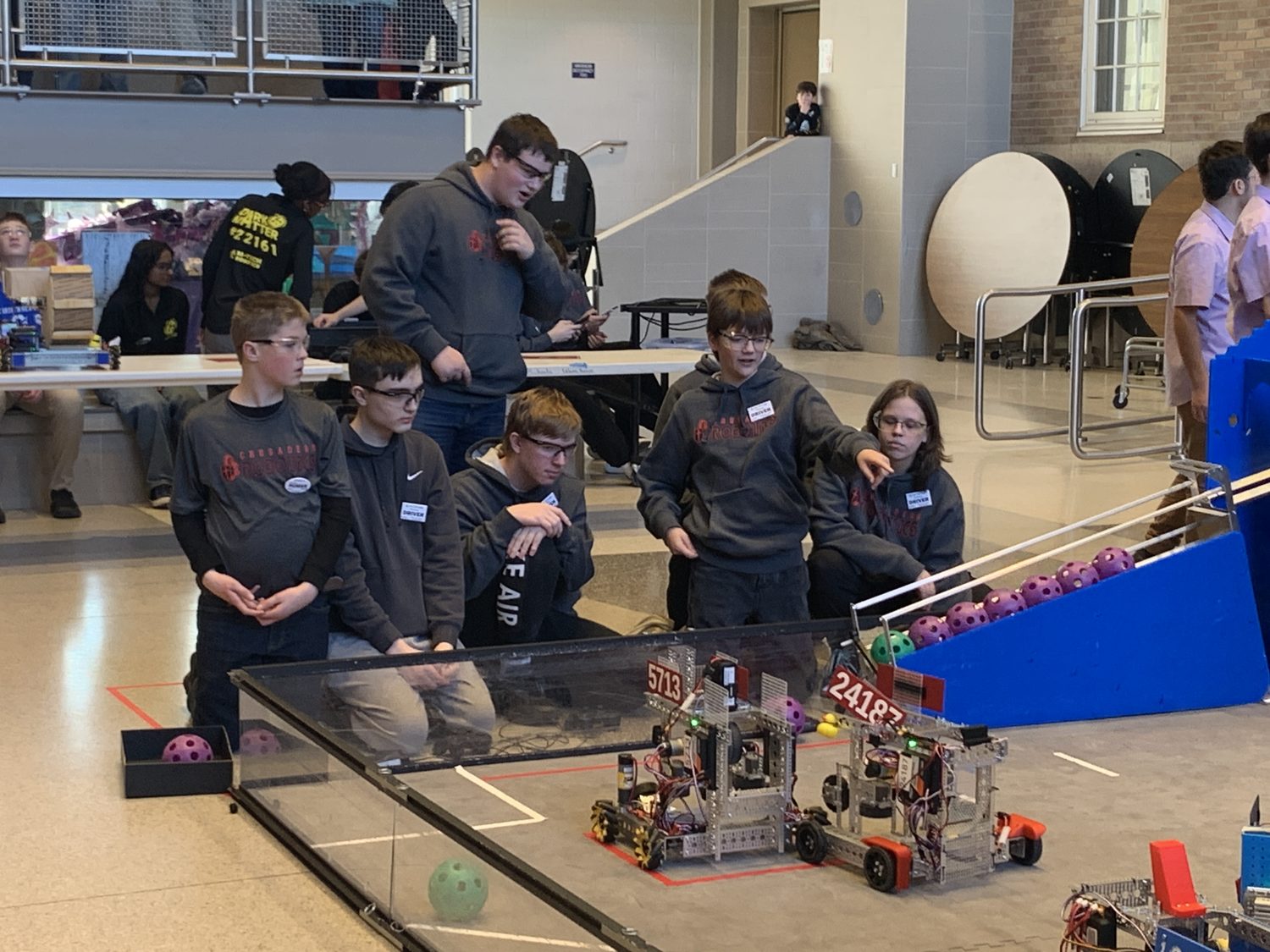 Crusader Robotics teammates lined up shoulder to shoulder at the competition field, controllers in hand