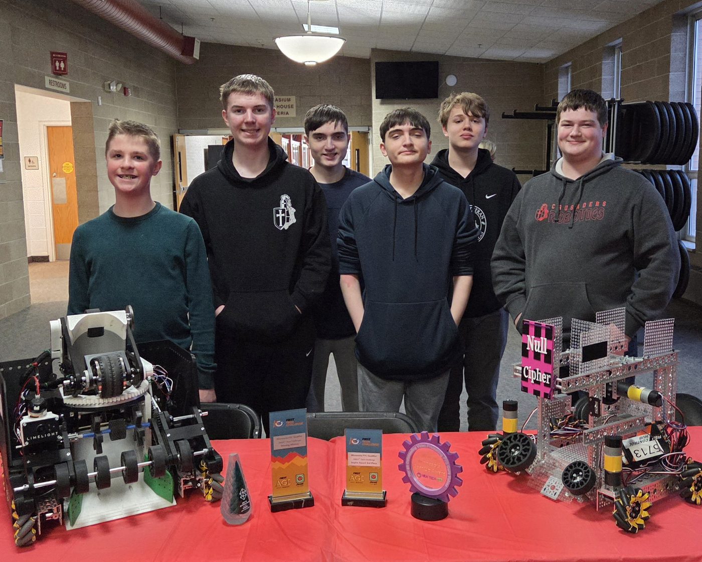Team 5713 Null Cipher students at the spring banquet, standing with the program's robots and trophies